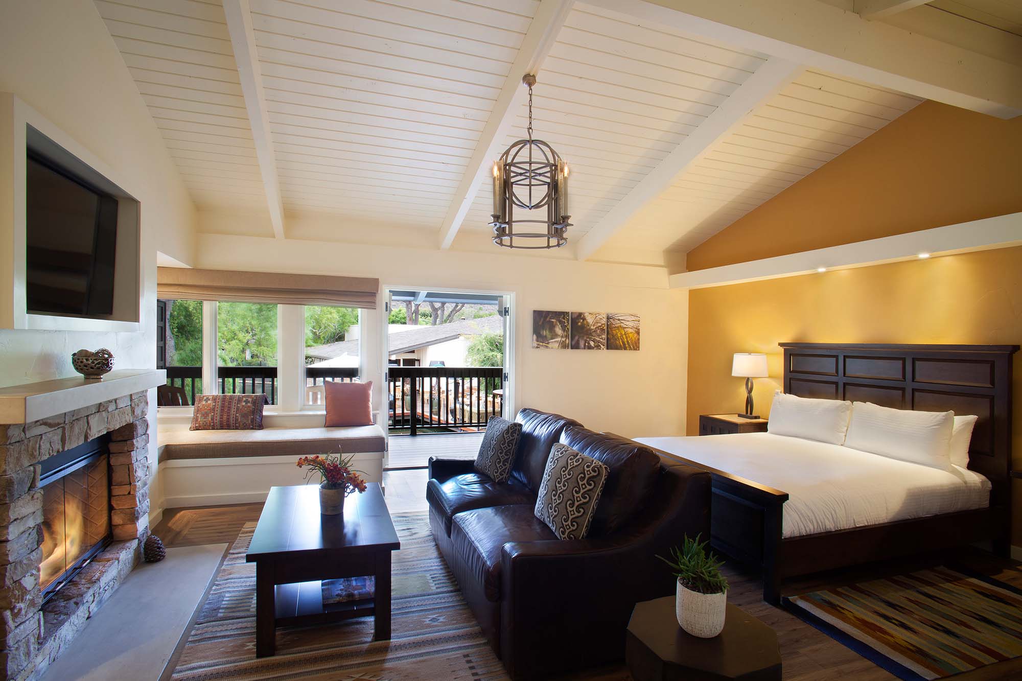 A large open fireplace sits below a flat screen TV in a Quail Lodge guest room in California