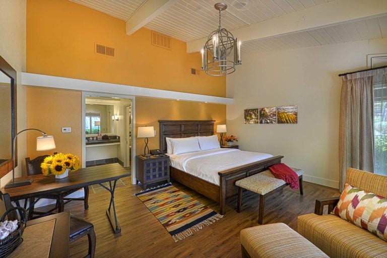 A large bed lies in a deluxe guest room at Quail Lodge Golf Resort in California