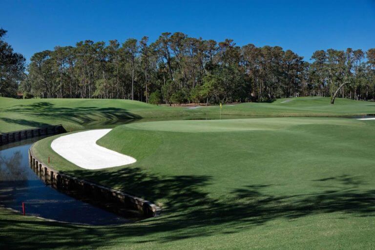 A raised green sits above a water canal and sand bunker on the eleventh hole at TPC Sawgrass golf course