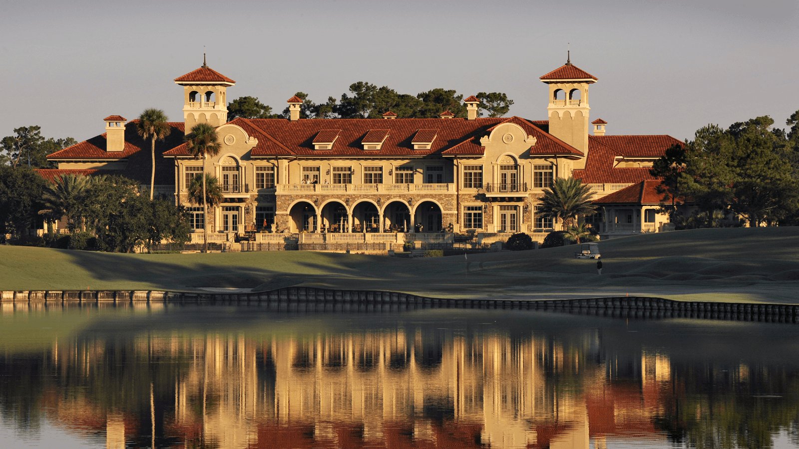 Dusk shines golden light on the golf course clubhouse at TPC Sawgrass