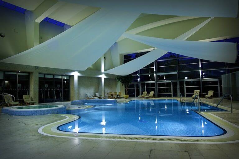 A large pool and shade sails at night in The K Club Resort