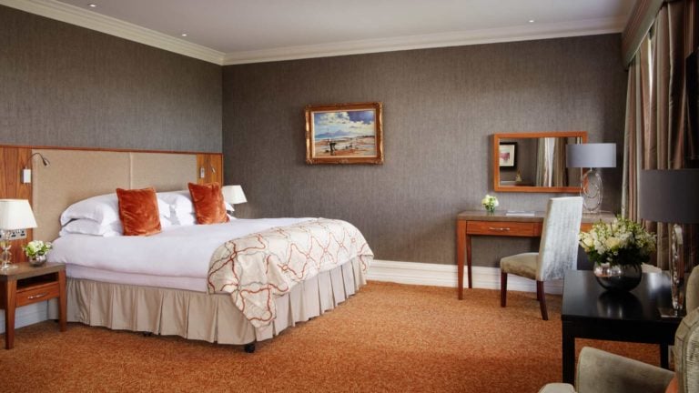 Interior view of a king bed and writing desk with a contemporary design at Slieve Donard Hotel