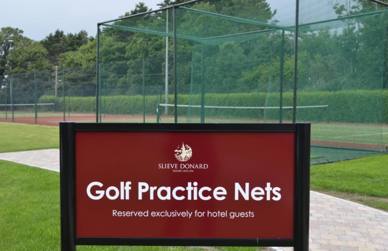 A sign saying 'golf practice nets' at Slieve Donard Hotel lying adjacent to the tennis courts