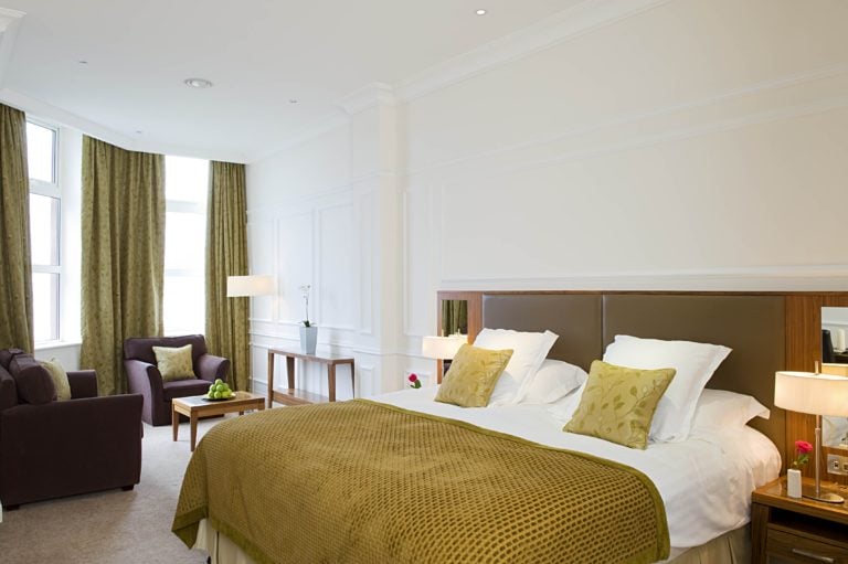 Interior bedroom view of a king bed and seating area at Slieve Donard Hotel