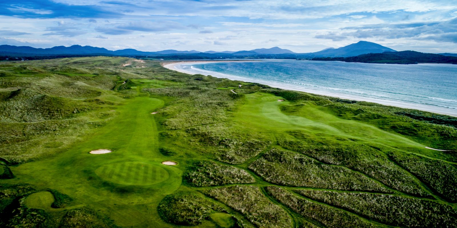 Aerial view of golf greens with fairways and undulating hills on the Old Tom Morris Golf Course at Rosapenna Golf Resort, Ireland