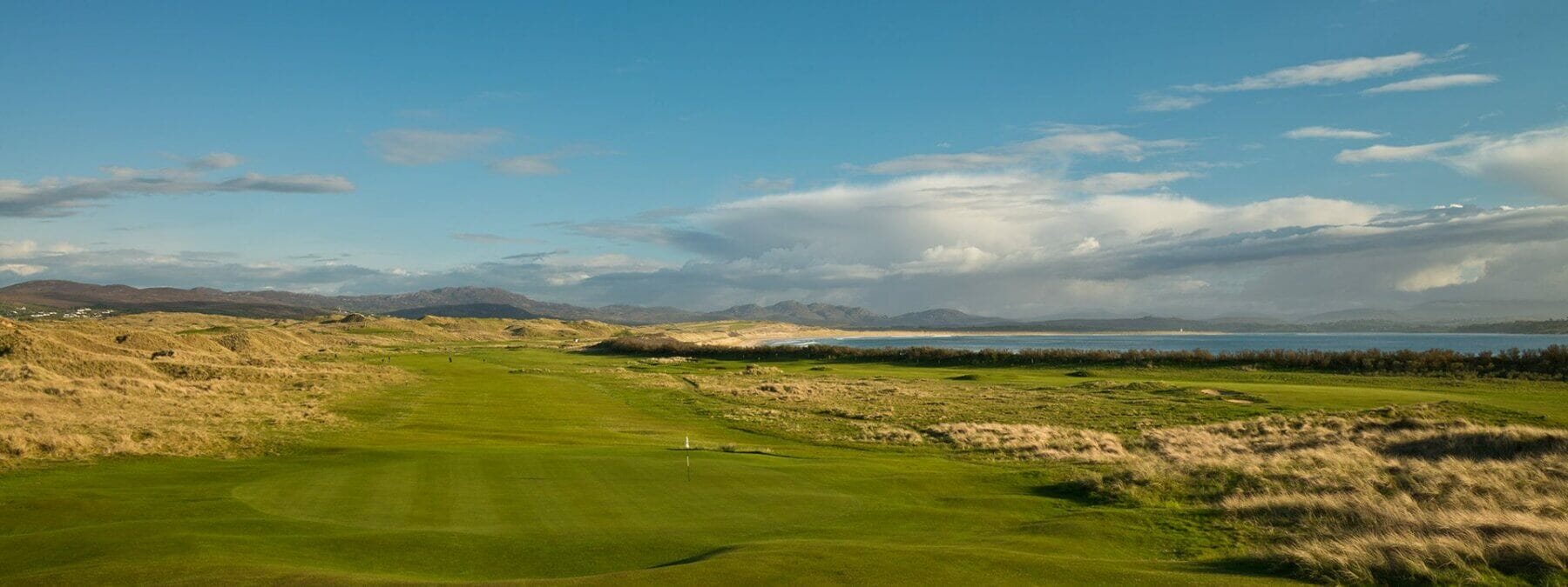 Landscape view of a green and long hazardous grass on the Old Tom Morris golf course at Rosapenna Golf Resort, Ireland