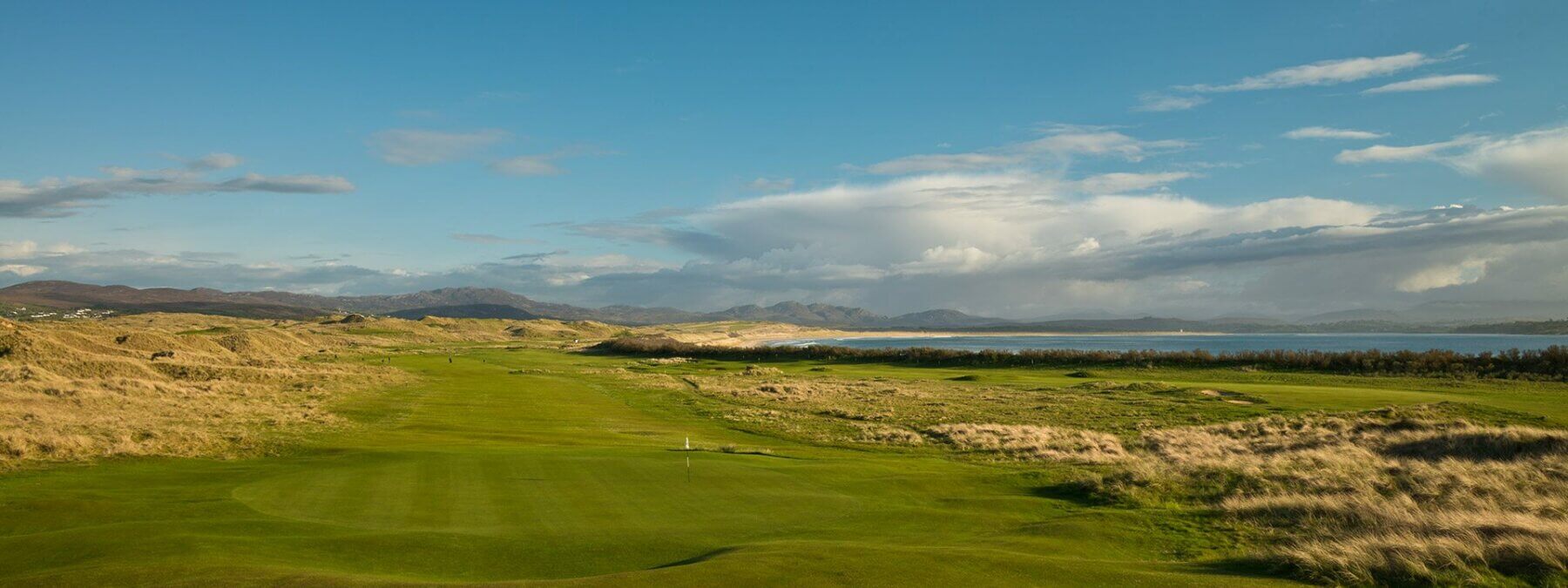 Landscape view of a green and long hazardous grass on the Old Tom Morris golf course at Rosapenna Golf Resort, Ireland