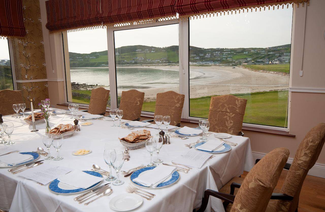 A dining table with beach and town views at Rosapenna Golf Resort, Ireland