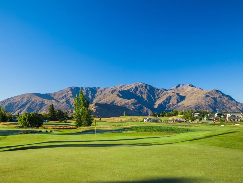 Image of a bright-blue ski over the Millbrook Resort Golf Course and distant mountainous backdrop in New Zealand