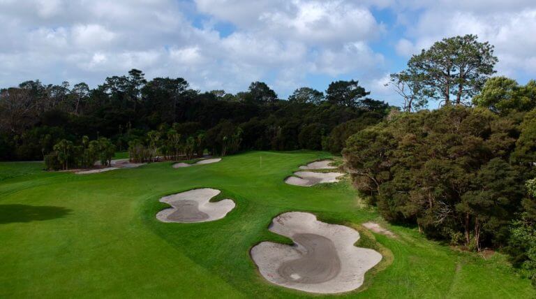 Aerial image overlooking fairway bunkers and the green surrounded by trees at Titirangi golf course