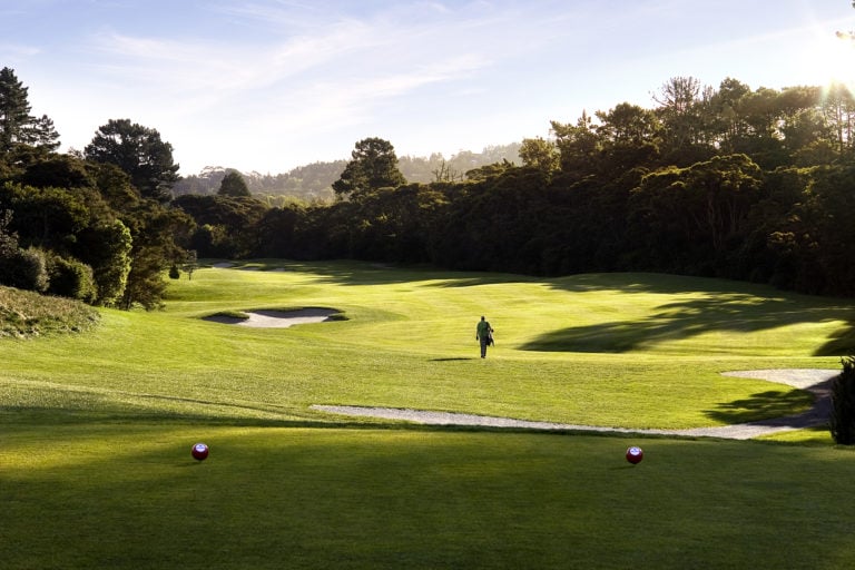 Image of a golfer walking down the 12th hole at Titirangi Golf Course, New Zealand