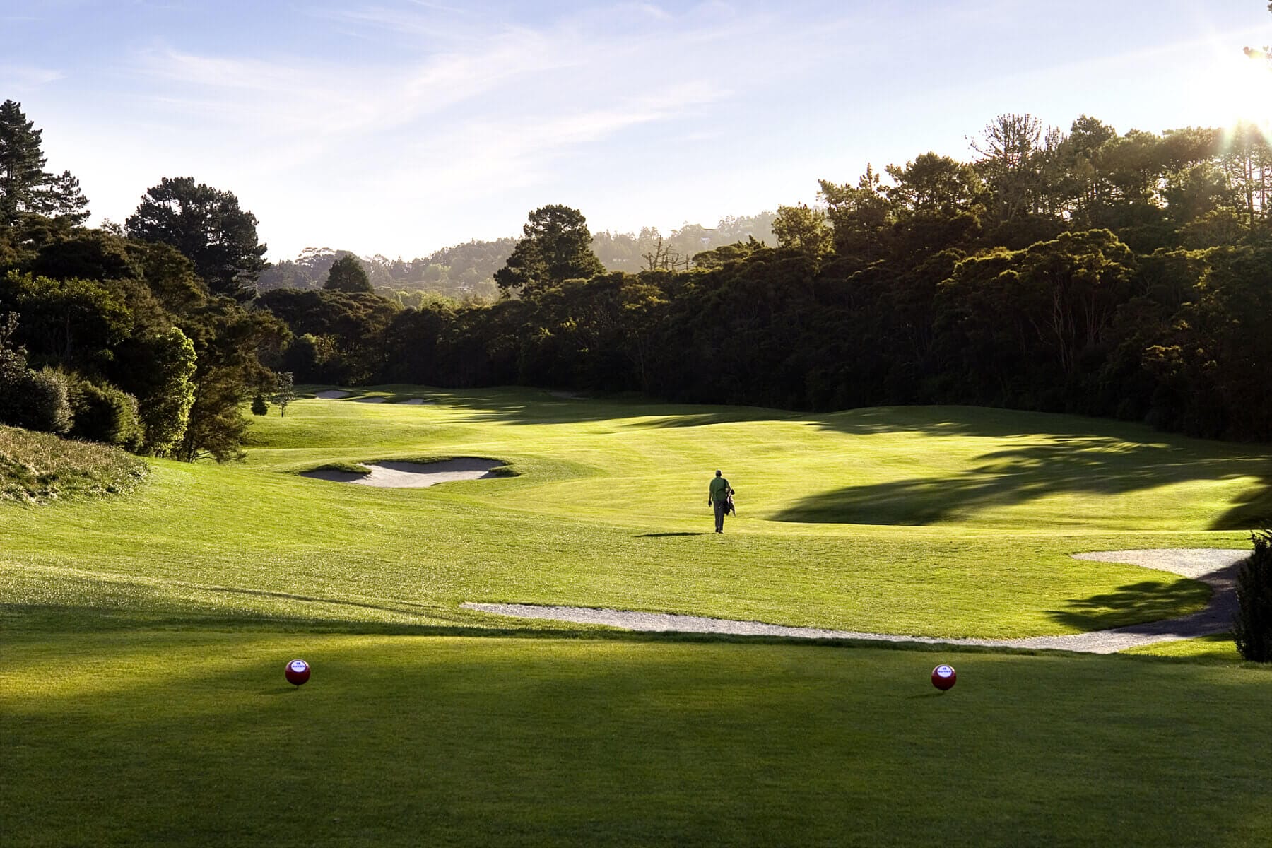 Image of a golfer walking down the 12th hole at Titirangi Golf Course, New Zealand