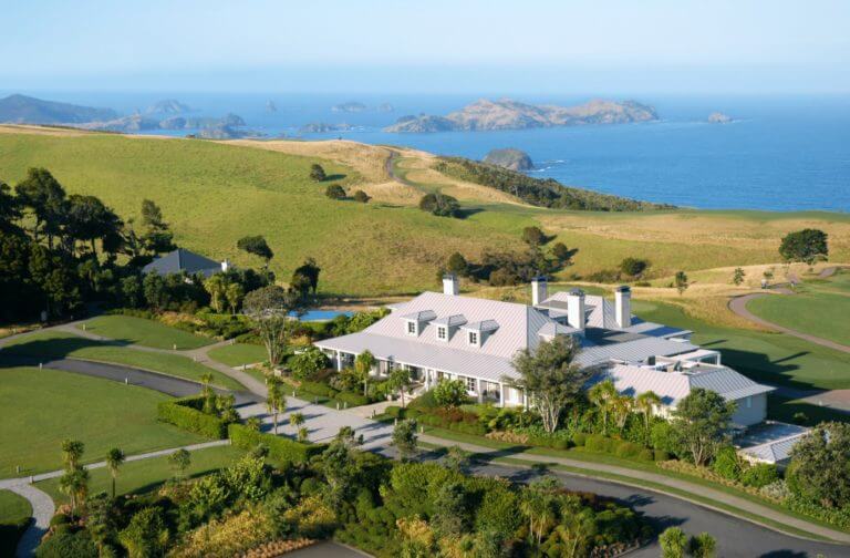 Image displaying Kauri Cliff's Lodge building and distant Bay of Islands, New Zealand's North Island