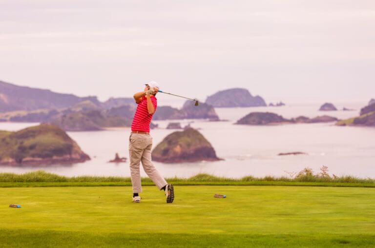 Image of a man teeing off on the Kauri Cliffs Golf Course, New Zealand's Matauri Bay