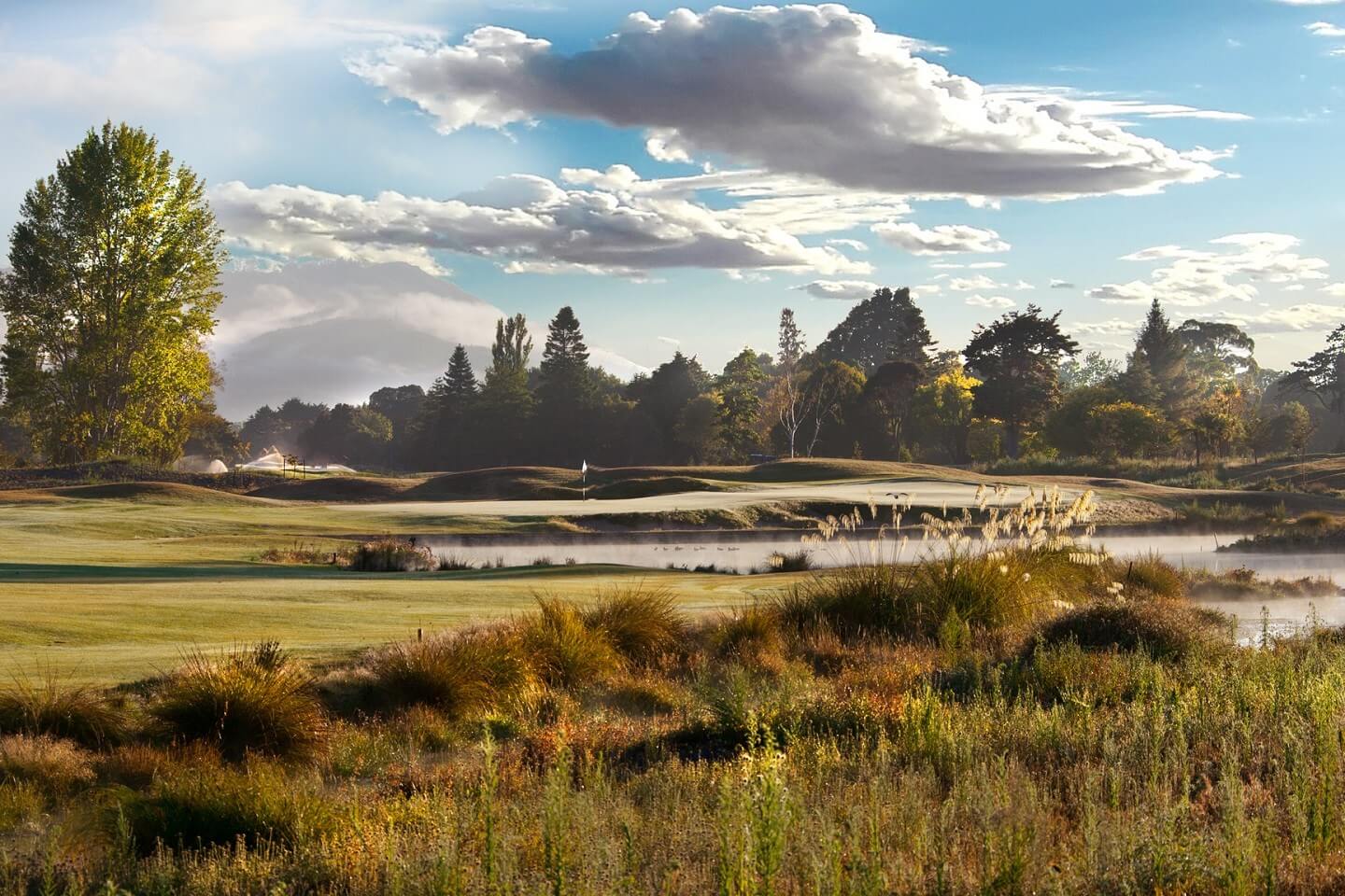 Large clouds float above a dew-covered golf course at Royal Wellington