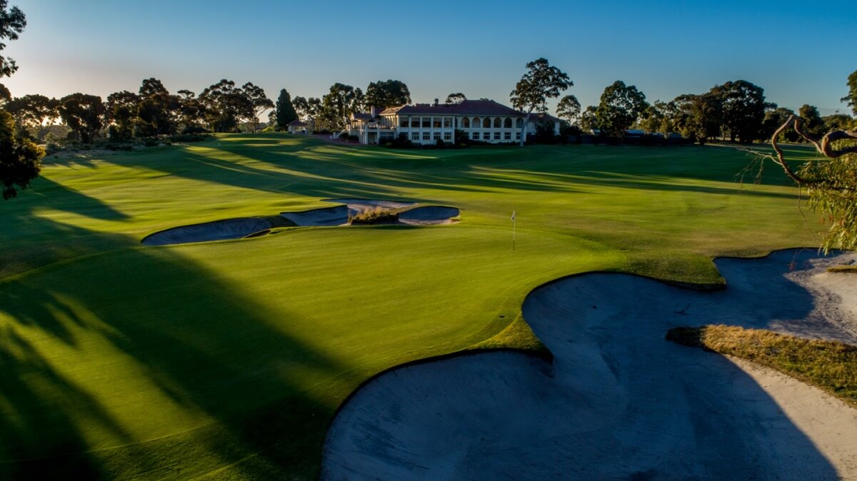 The Commonwealth golf clubhouse sits in the distance with a green and large bunker in the foreground