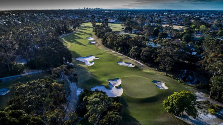 Aerial view of the well-manicured first hole and distant Melbourne city
