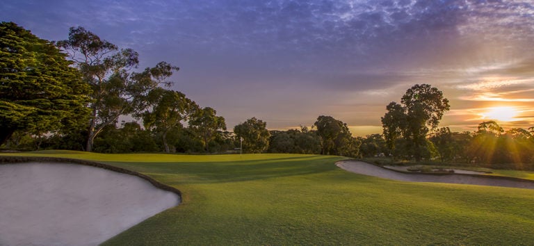 The sun sets over a Sandbelt golf green at Victoria Golf Club