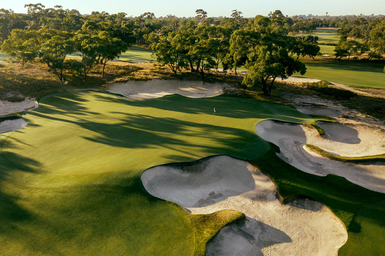 Aerial view of a raised green with dusk casting golden light at Peninsula Kingswood South Course