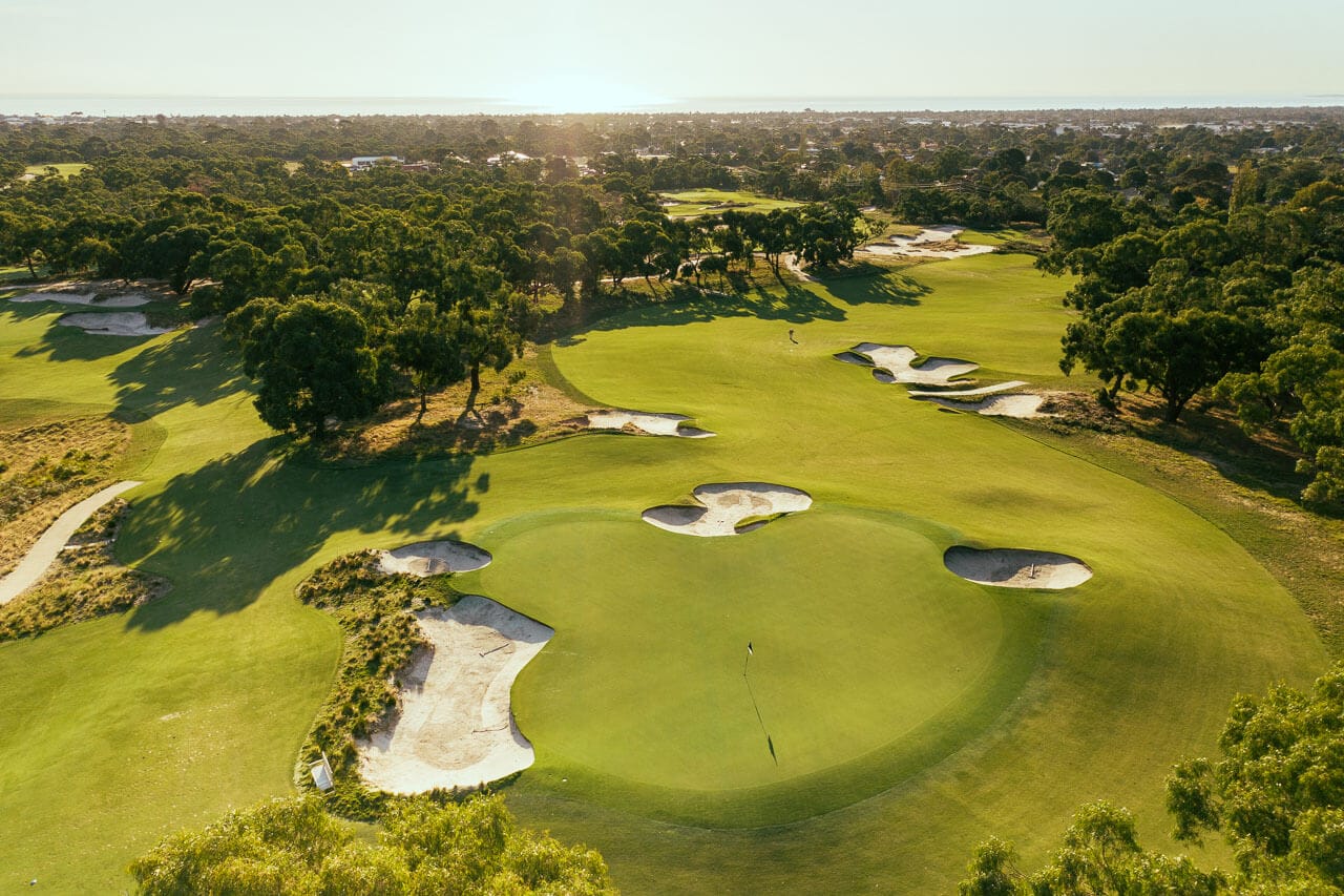 A large plateaued green is surrounded by sandbelt bunkers