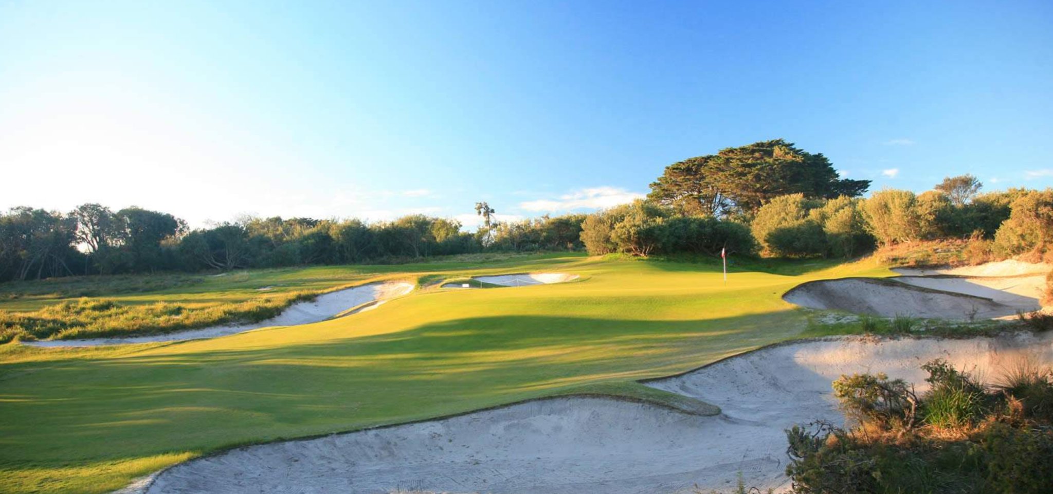 A large green is flanked by two larger bunkers on the East golf course