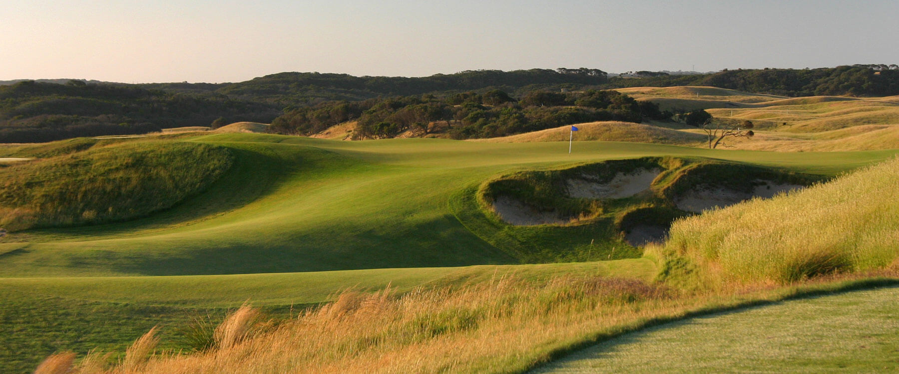 A raised plateaued green with blue flag stick on the Moonah course