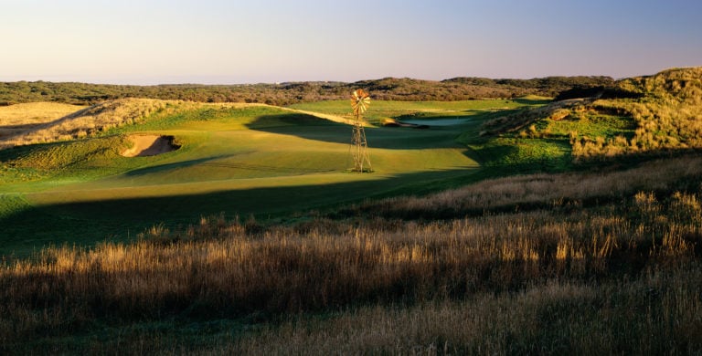 Golden sunset light shines on the tenth hole windmill of the Moonah course