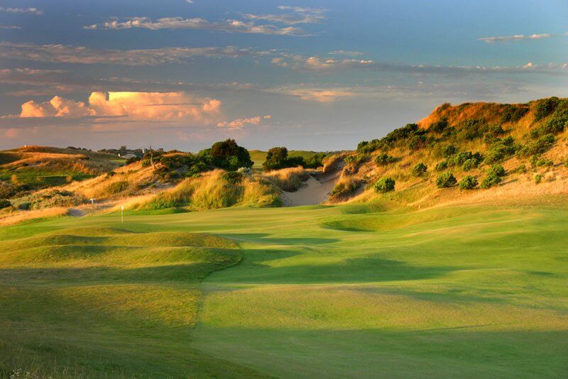 A wide-open fairway leads to a downhill green on The Dunes golf course