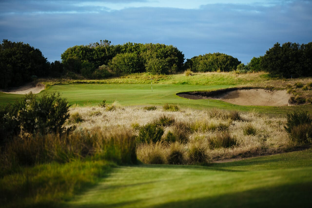 A distant golf flag stick view-able from a tee box