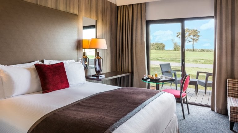 Double bed and balcony adorn a golf view room at the resort