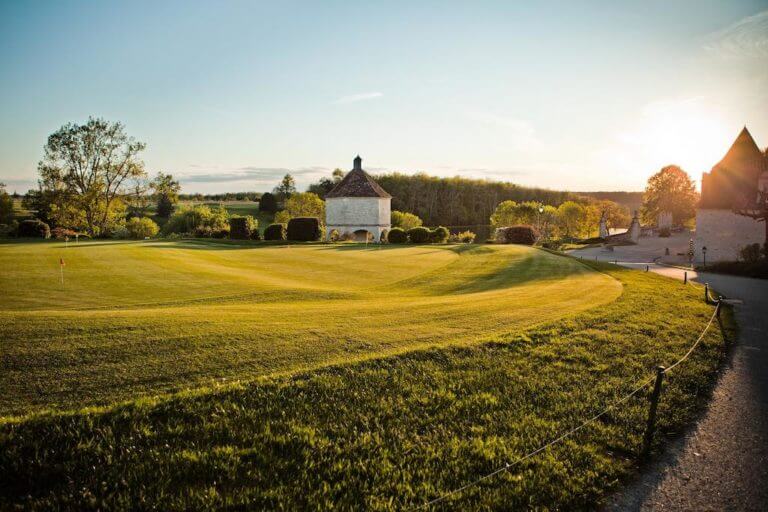 Golden light from sunset shines on the practice putting green at Chateaux de Vigiers
