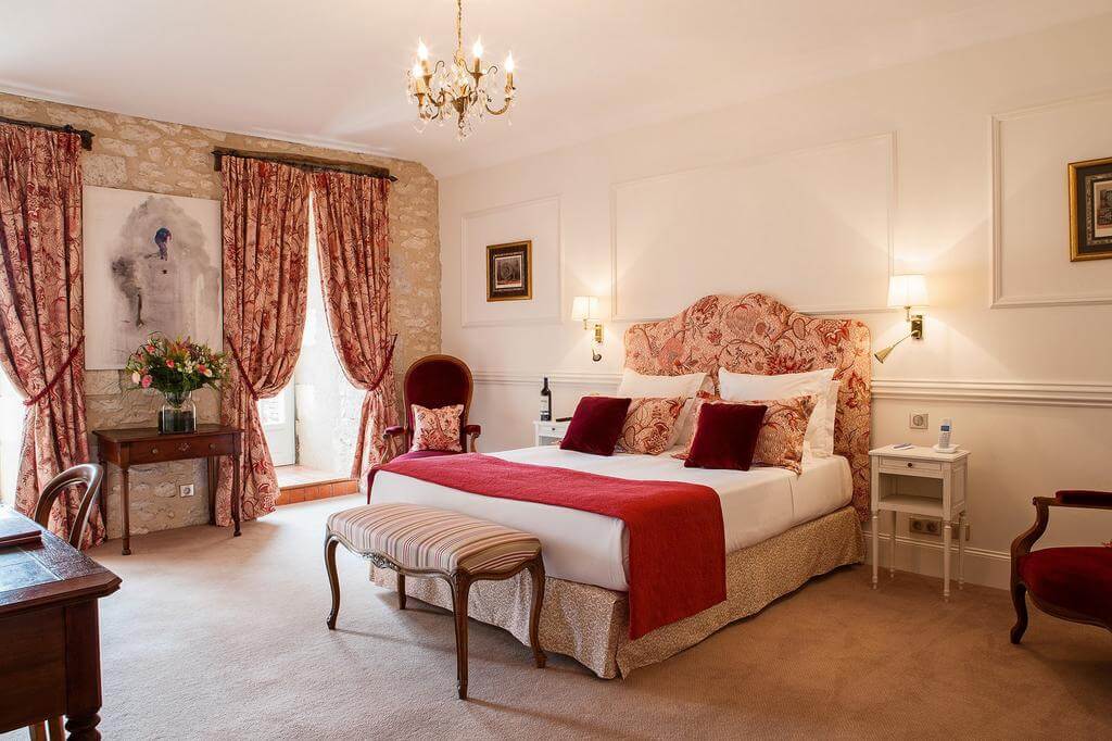 Old-style designed bedroom with warm red tones at Chateaux de Vigiers