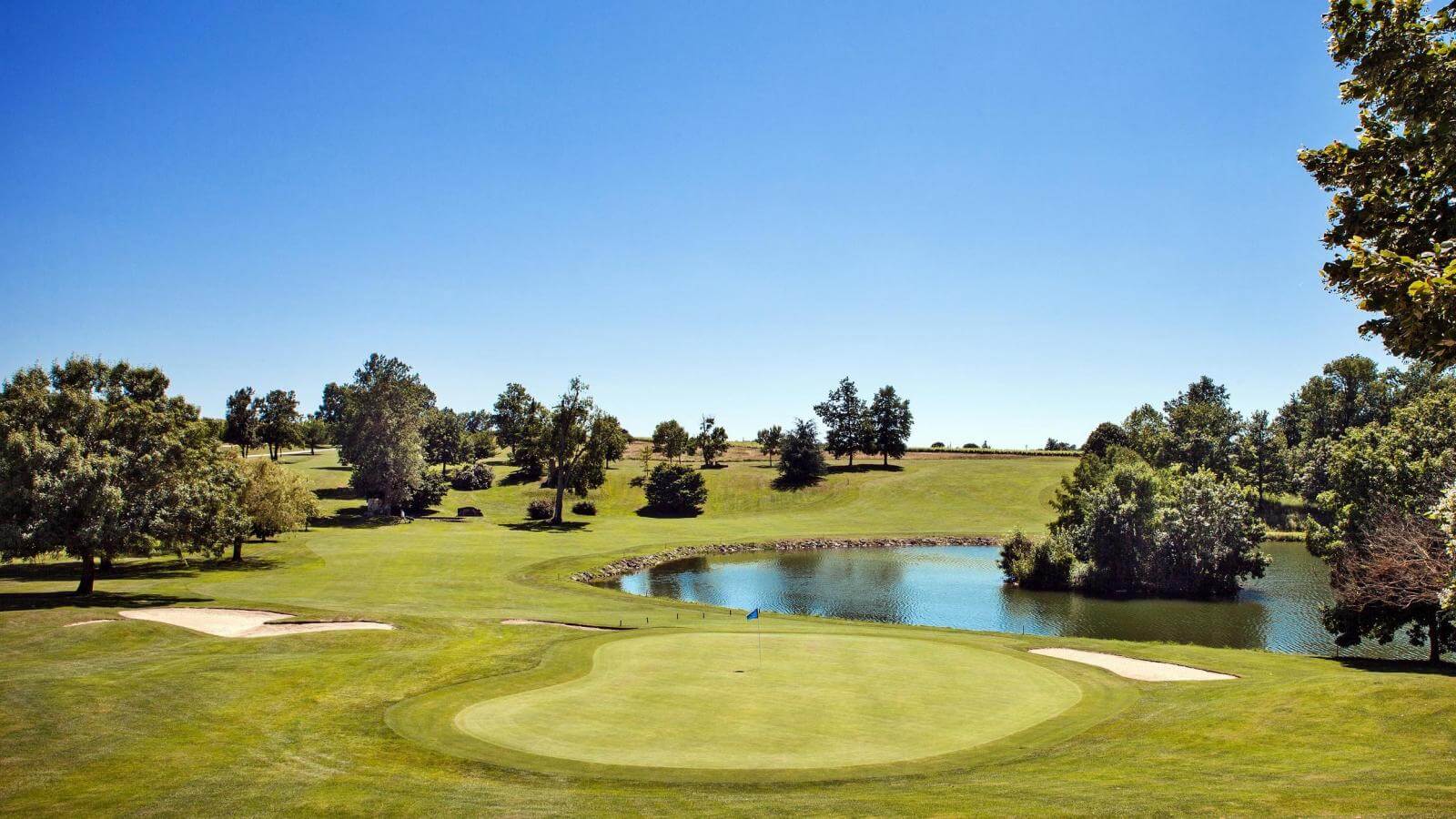 A large green is protected by bunkers and lake on the golf course