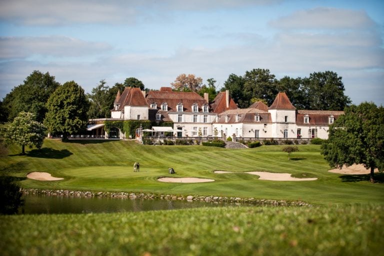 External view of the Chateaux des Vigiers Resort with golfers on the eighteenth green