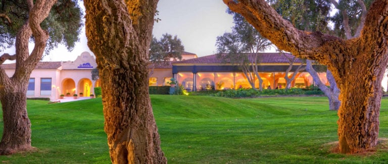 Light shines from the clubhouse through cork trees at Real Club Valderrama golf course