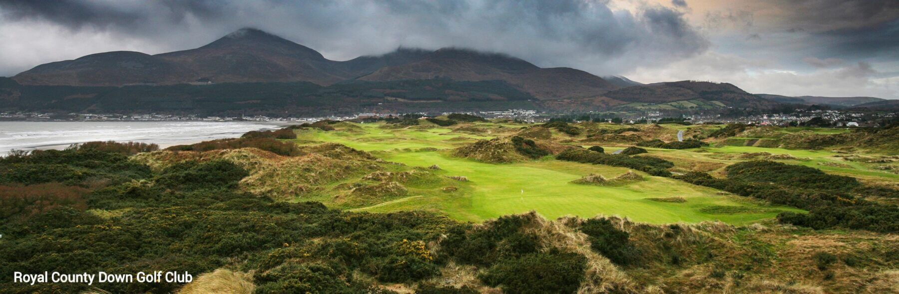 Landscape view of the Royal Country Down Golf Club and distant mountains