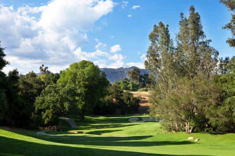 View looking down the Ojai Valley Inn Golf Course with large trees flanking the course
