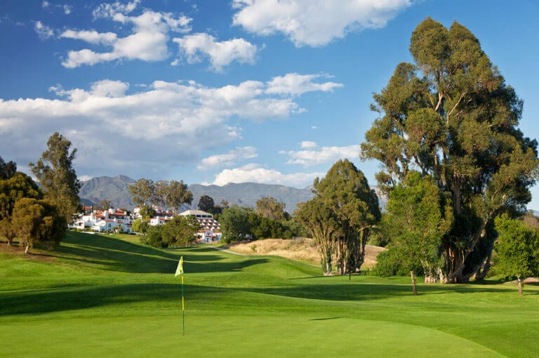 A green stands in the foreground with the main Ojai Valley Inn resort complex in the background