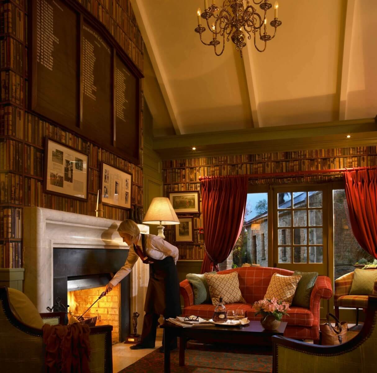 A waitress stokes an open fire in the Gallery at Dromoland Castle Hotel
