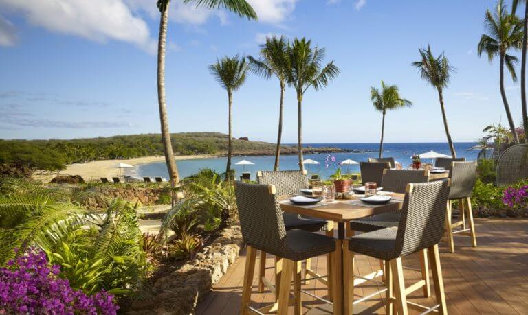 A dining table overlooks a private beach at Lanai Four Seasons Resort