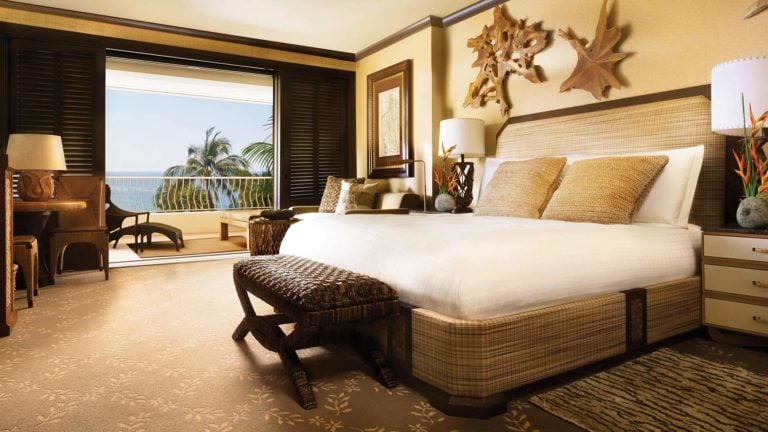 Interior view of a large king bedroom with private balcony with ocean views