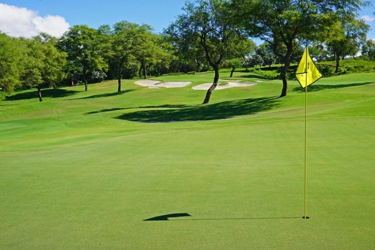 A yellow golf flag stands in the fourteenth green of the Emerald Course at Wailea