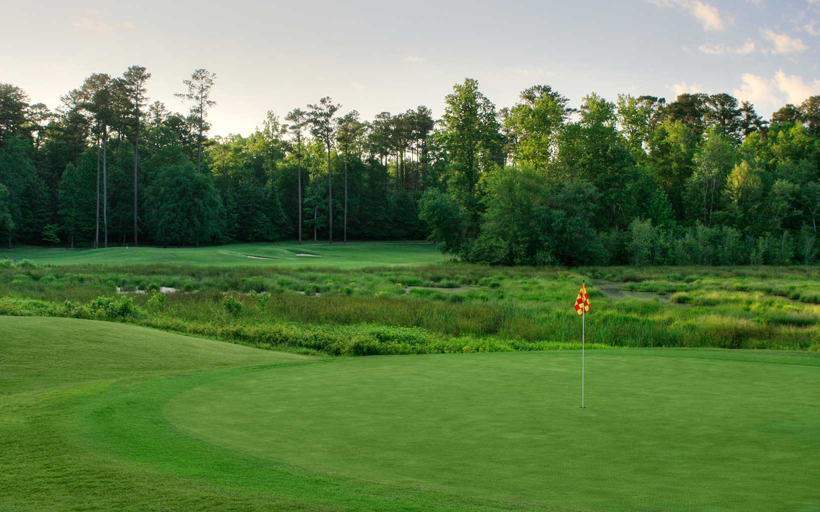 A red and yellow checked flag stands on the thirteenth hole at Grand National Links course