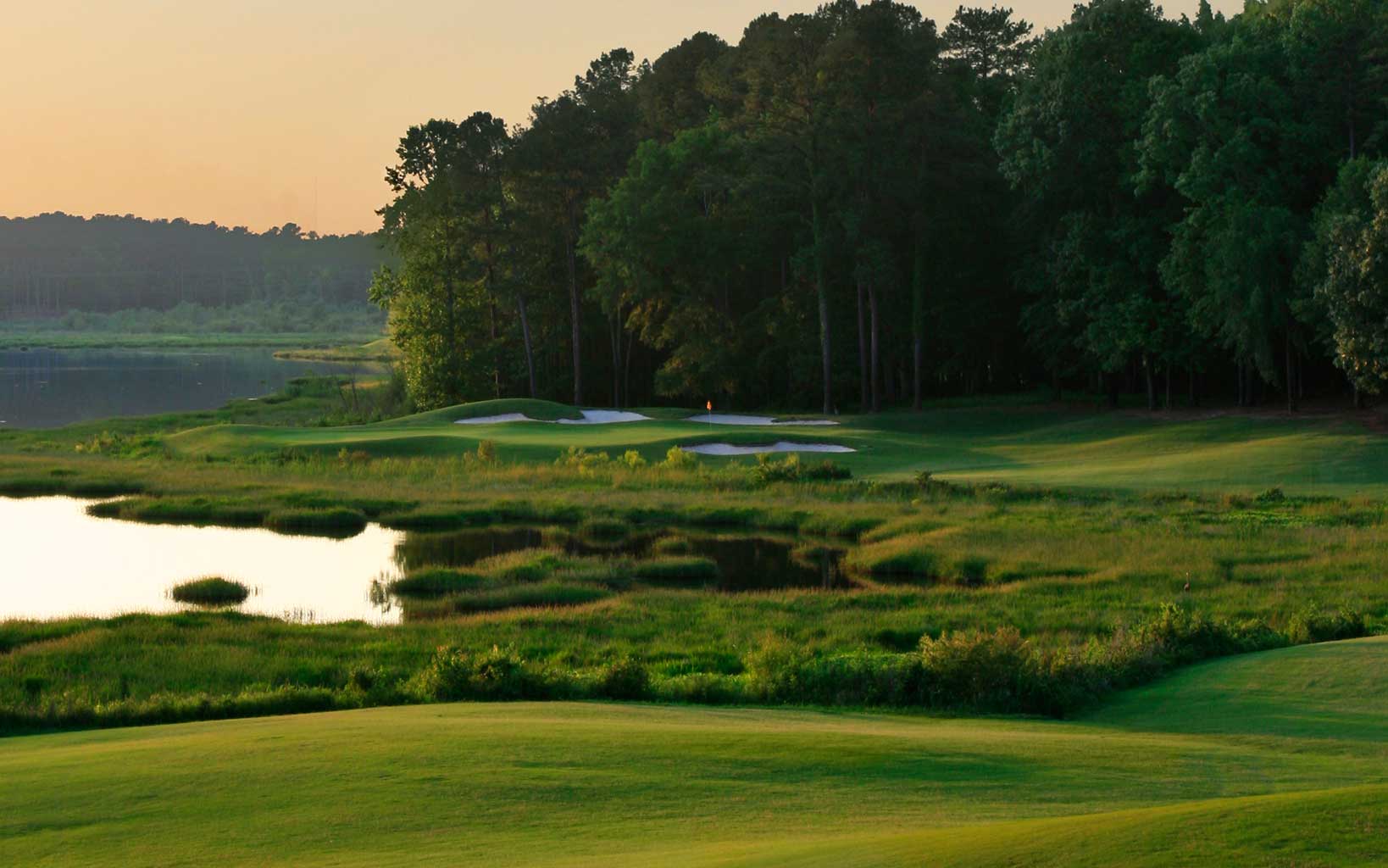 The setting sun shines over the fourth green on the links course