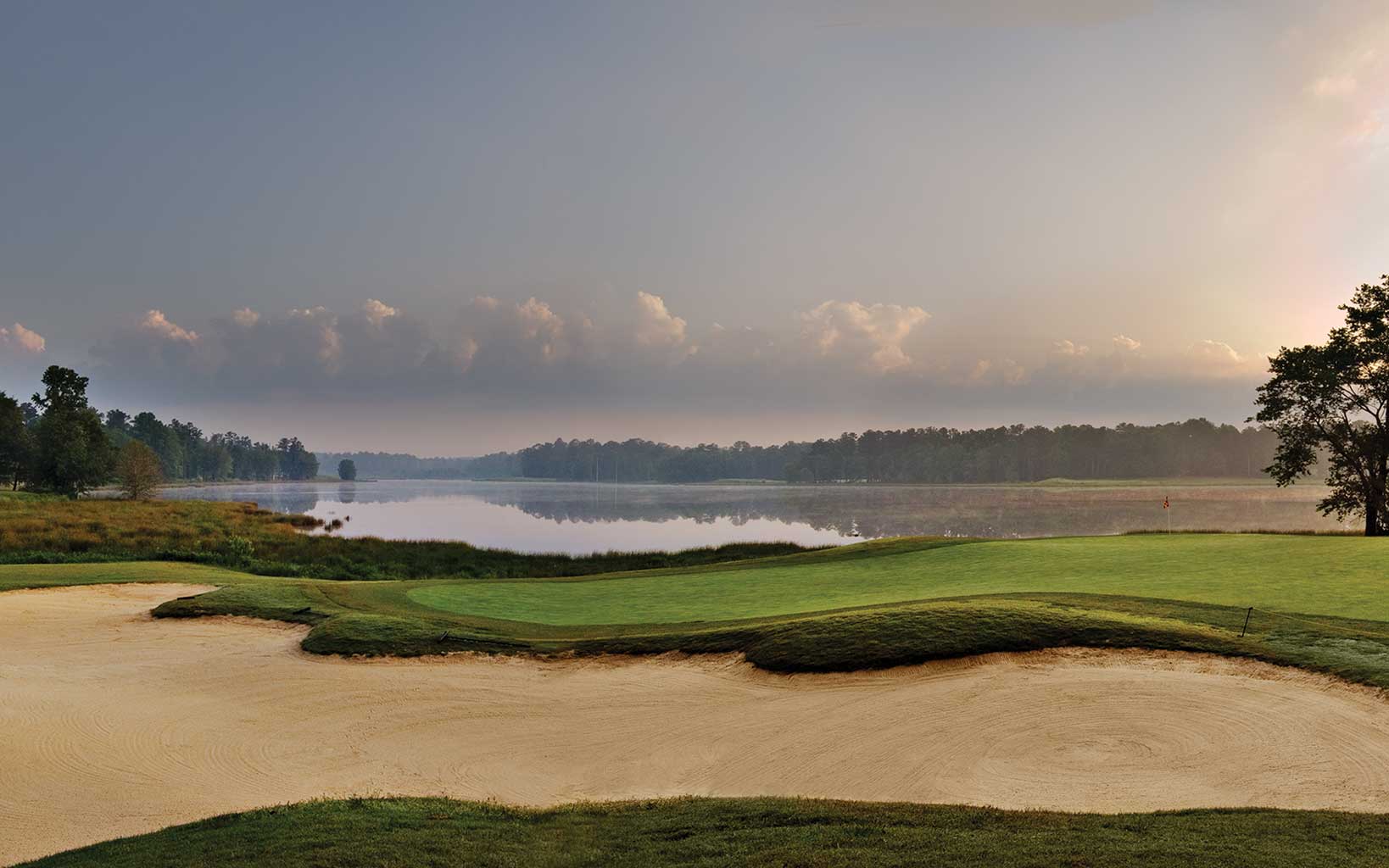 A large bunker surrounds the third green at Grand National Golf Club