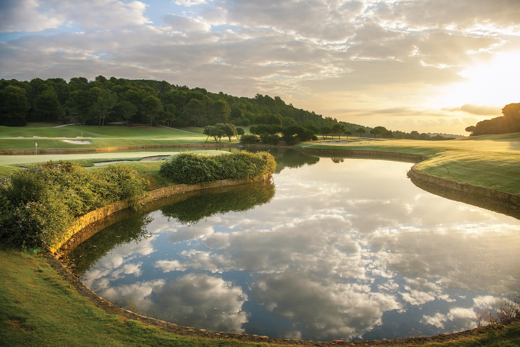 Clouds reflect off a still lake at La Reserva Club