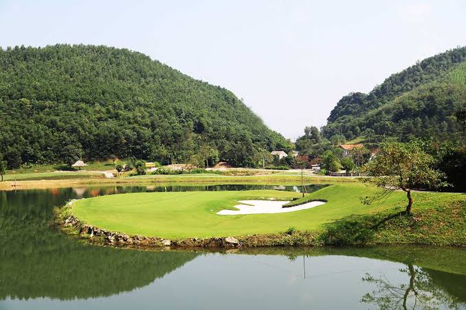 A green is protected on three sides by a lake and bunker