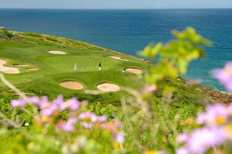 Golfers stand around a green and bunkers at Pinnacle Point Golf Course