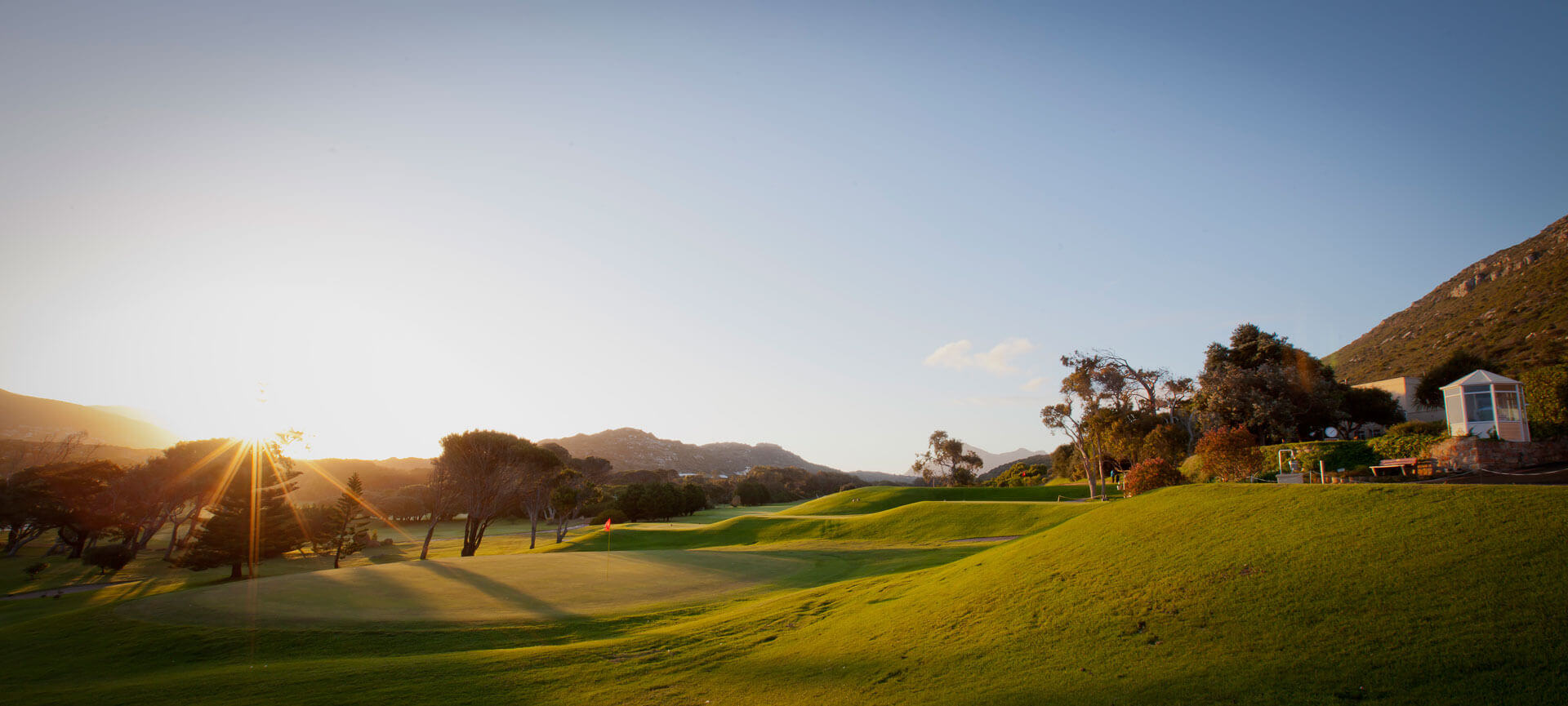 Golden sunlight casts long shadows over the eighteenth green