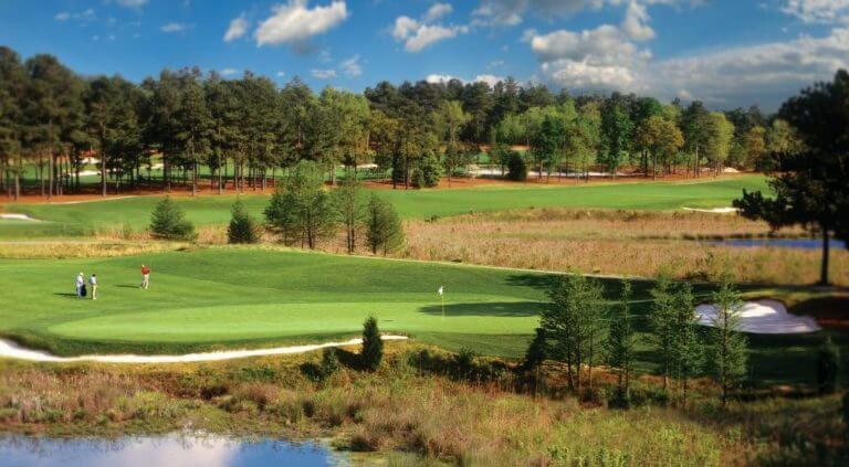 Golfers play on a raised green with retaining wall